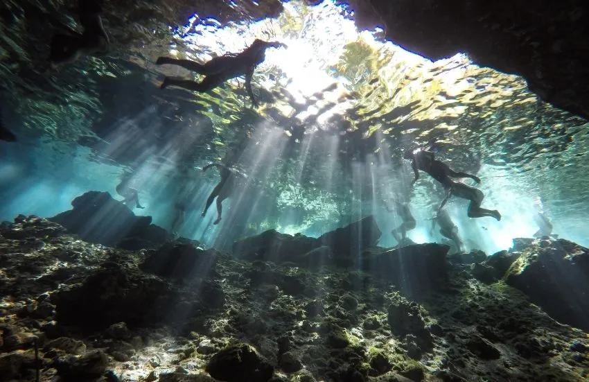 Menschen schwimmen in einer Cenote in Cancun am Strand in Mexiko.